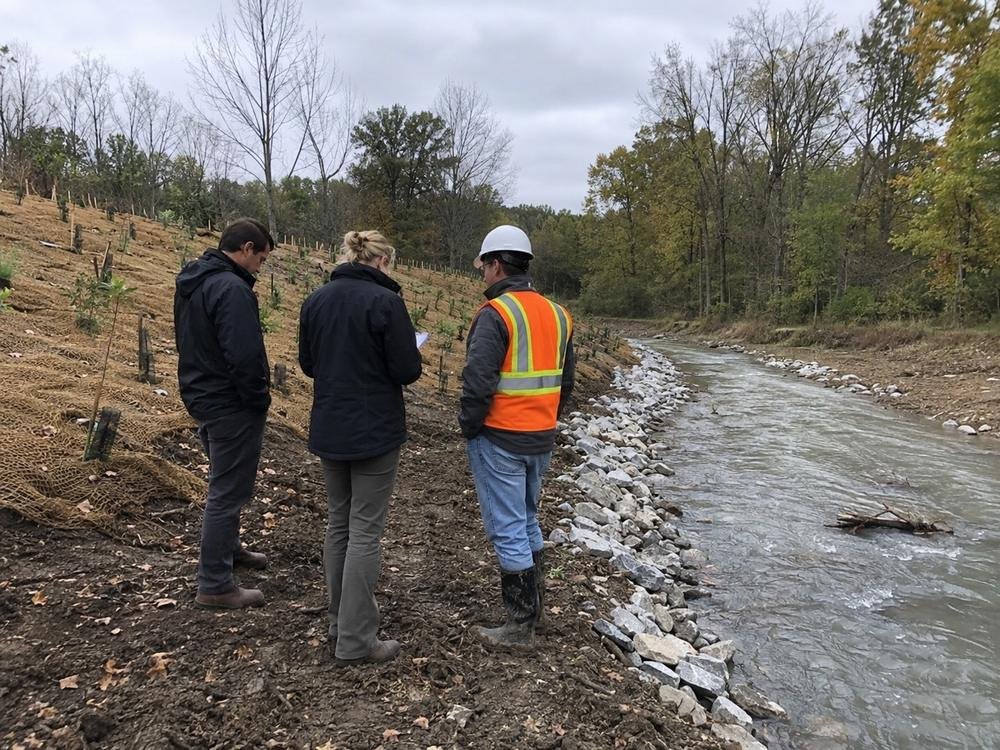 A stabilized streambank with riprap, erosion matting and new plantings, reviewed on site with the contractor